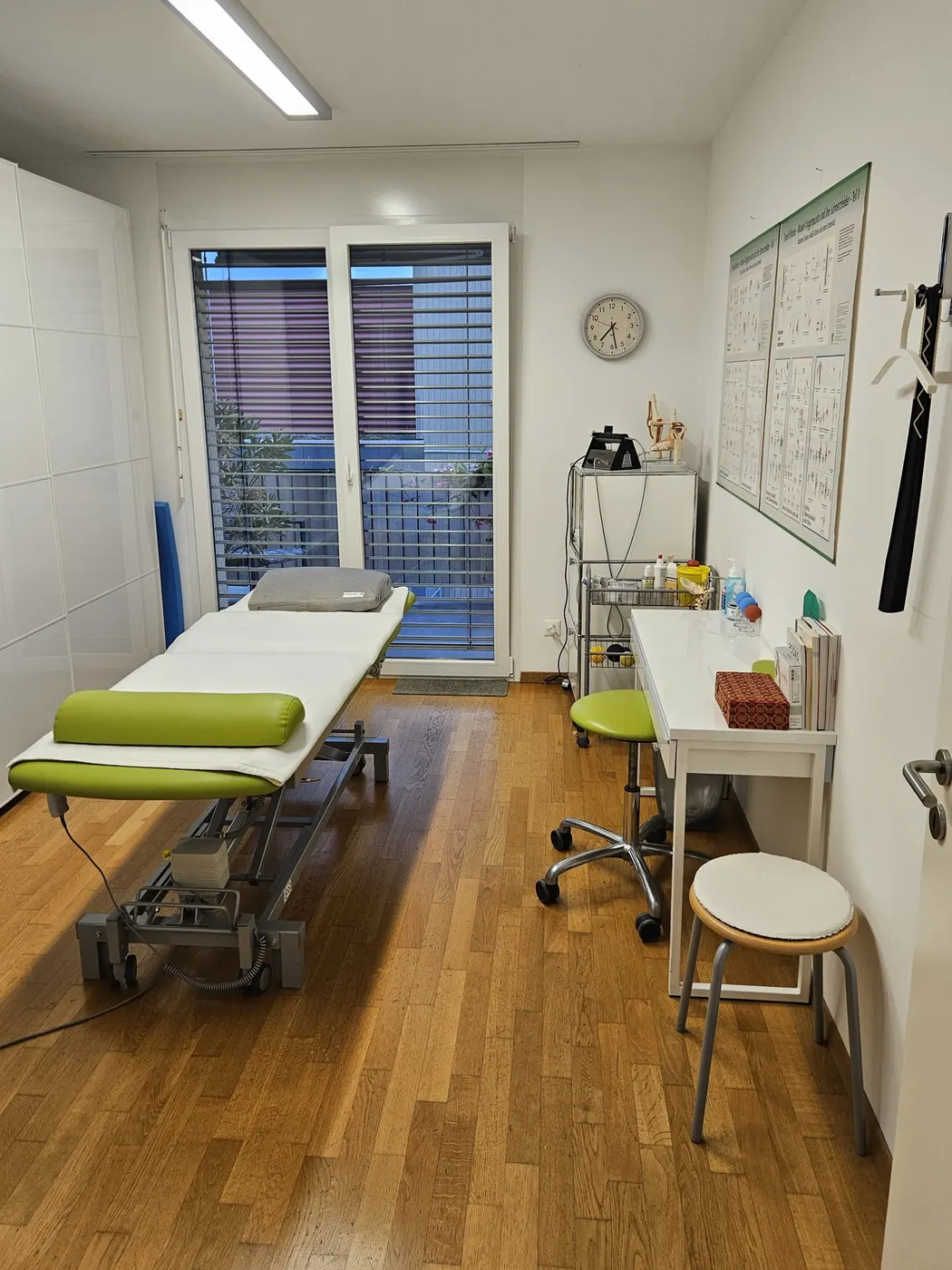 Treatment room in Arni AG: treatment table, desk and anatomy charts