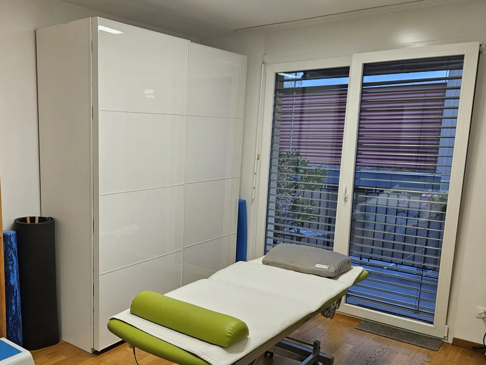 Behandlungsraum der Praxis Somanti in Arni AG mit Behandlungsliege und Fenster zum Garten